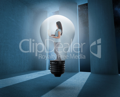 Composite image of woman holding laptop in light bulb