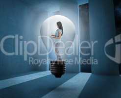 Composite image of woman holding laptop in light bulb