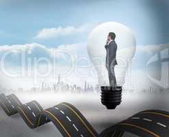 Composite image of thinking businessman in light bulb