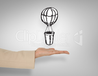 Composite image of female hand presenting hot air balloon