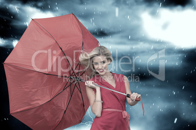 Composite image of smiling blonde holding umbrella