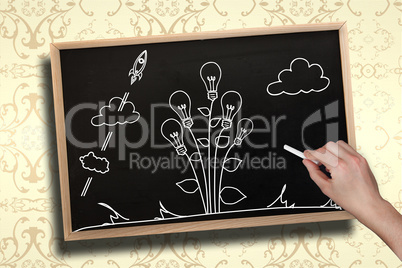 Composite image of hand drawing light bulb plant with chalk