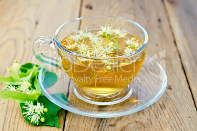 Herbal tea of linden flowers in glass cup on board