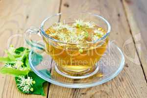 Herbal tea of linden flowers in glass cup on board