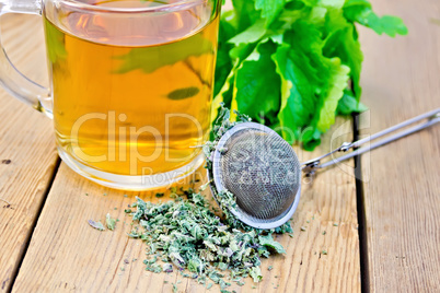 Herbal tea with mint in mug with strainer on board