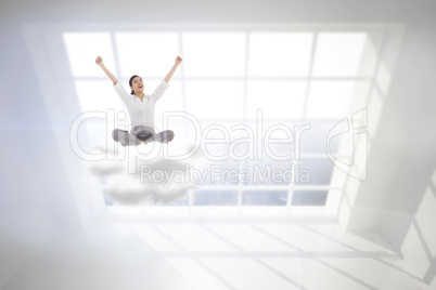 Composite image of cheering businesswoman sitting cross legged