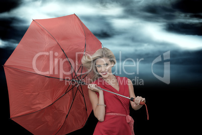 Composite image of smiling blonde holding umbrella