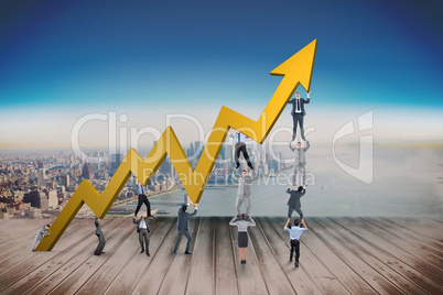 Composite image of business team holding up arrow