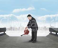 Composite image of mature businessman using watering can