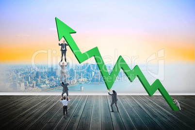 Composite image of business team holding up arrow