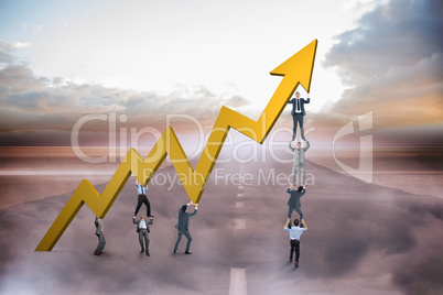 Composite image of business team holding up arrow