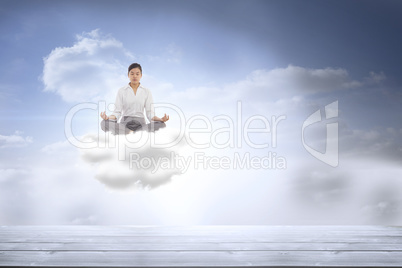 Composite image of businesswoman sitting in lotus pose