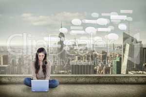 Composite image of brunette sitting on floor using laptop