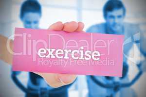 Woman holding pink card saying exercise