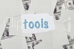 Tools against white paper strewn over dollar bills
