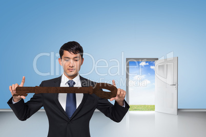 Composite image of unsmiling businessman carrying large key