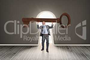 Composite image of businessman carrying large key