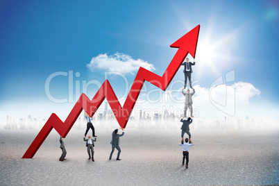 Composite image of business team holding up arrow