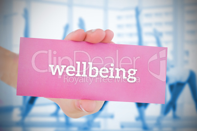 Woman holding pink card saying wellbeing