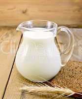 Milk in glass jug with bread on board