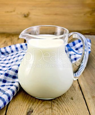 Milk in glass jug with napkin on board