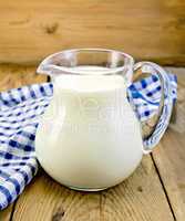 Milk in glass jug with napkin on board