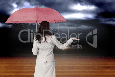 Composite image of businesswoman holding umbrella