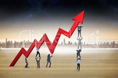 Composite image of business team holding up arrow