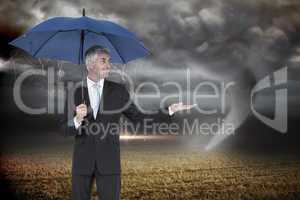 Composite image of happy businessman holding umbrella