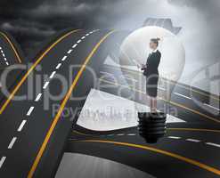 Composite image of businesswoman holding tablet in light bulb