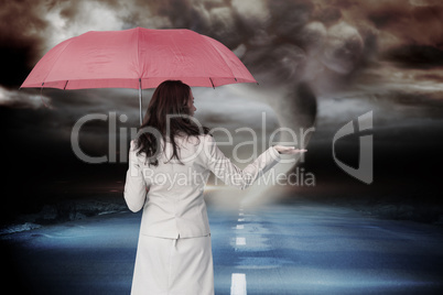 Composite image of businesswoman holding umbrella