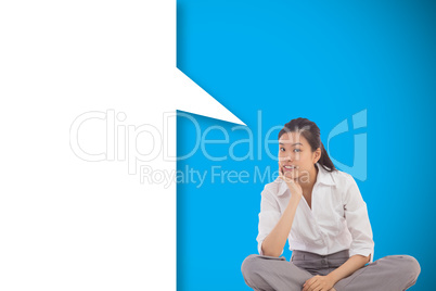 Composite image of businesswoman sitting cross legged thinking w