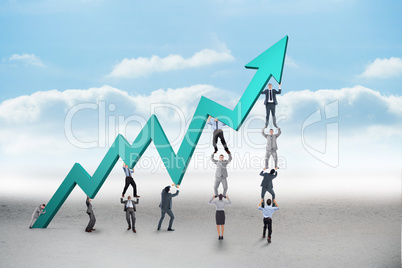 Composite image of business team holding up arrow