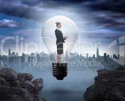 Composite image of businesswoman holding tablet in light bulb