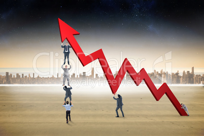 Composite image of business team holding up arrow