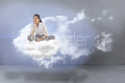 Composite image of businesswoman sitting cross legged thinking