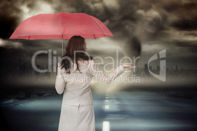 Composite image of businesswoman holding umbrella