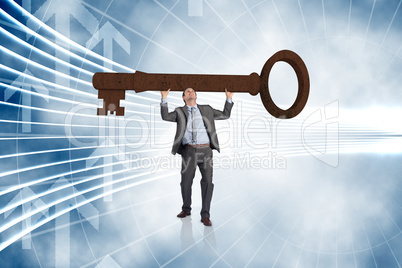 Composite image of businessman carrying large key with arms rais