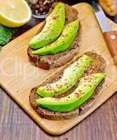Sandwich with avocado and lemon on board