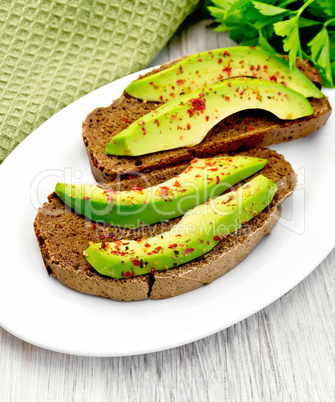 Sandwich with avocado and parsley on light board