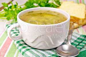 Soup of green peas with bread on tablecloth