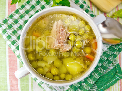 Soup of green peas with meat on tablecloth