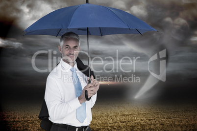 Composite image of businessman holding blue umbrella