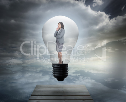 Composite image of thinking businesswoman in light bulb
