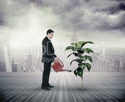 Composite image of businessman holding red watering can