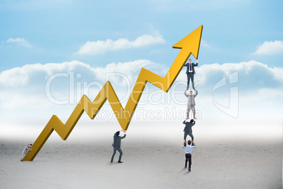 Composite image of business team holding up arrow