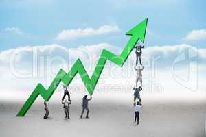 Composite image of business team holding up arrow