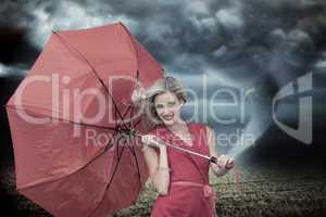 Composite image of smiling blonde holding umbrella