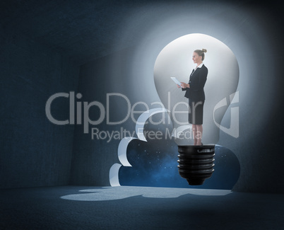 Composite image of businesswoman holding tablet in light bulb