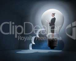 Composite image of businesswoman holding tablet in light bulb